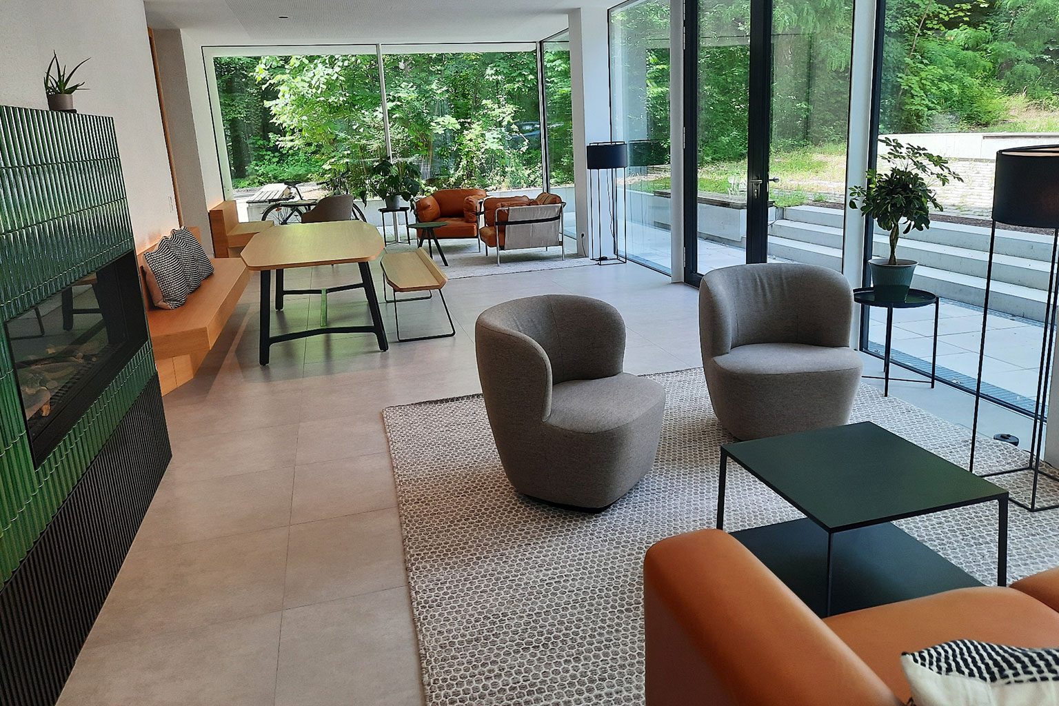View of a common room with a large dining table, armchairs and tables.