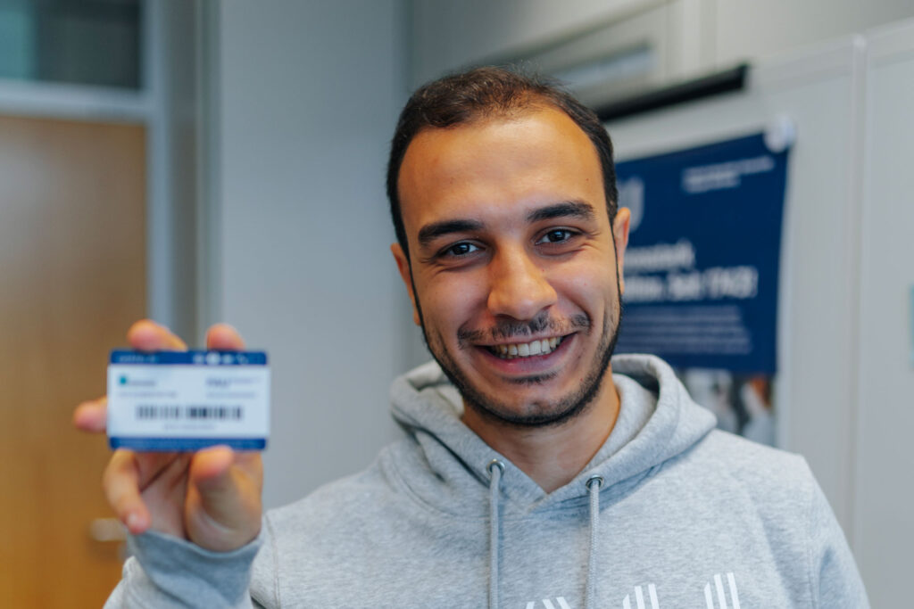 Mann hält eine FAUcard in die Kamera