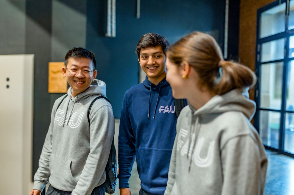 Drei Menschen laufen einen Gang entlang und unterhalten sich.