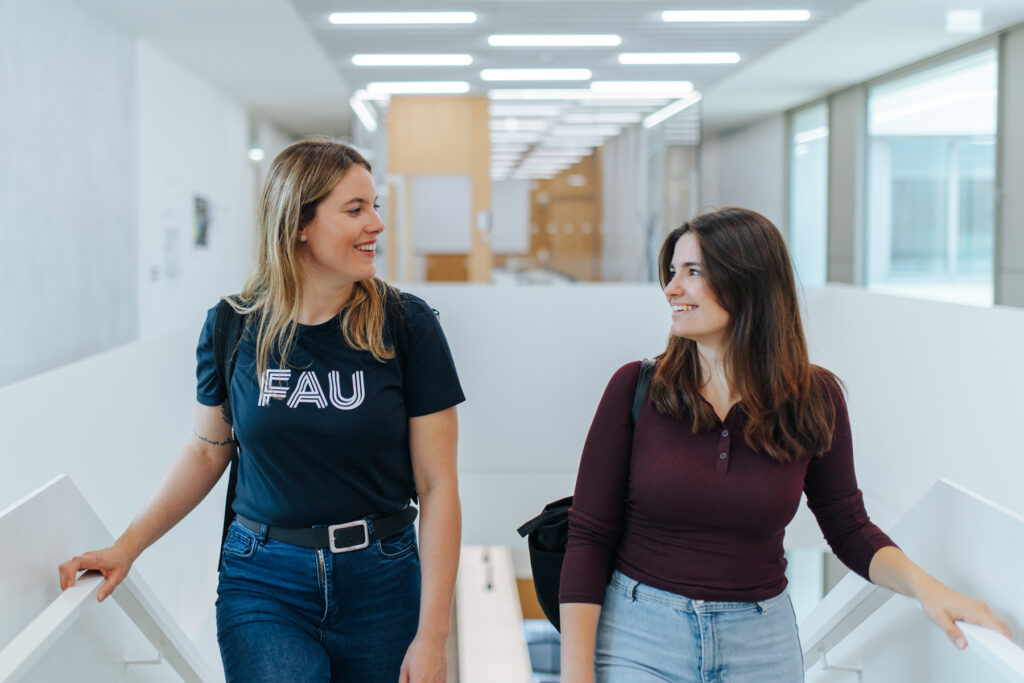 Zwei Studierende gehen eine Treppe hinauf und unterhalten sich.