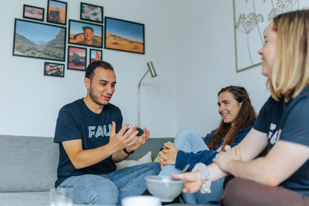 Drei Studierende sitzen auf dem Sofa und unterhalten sich