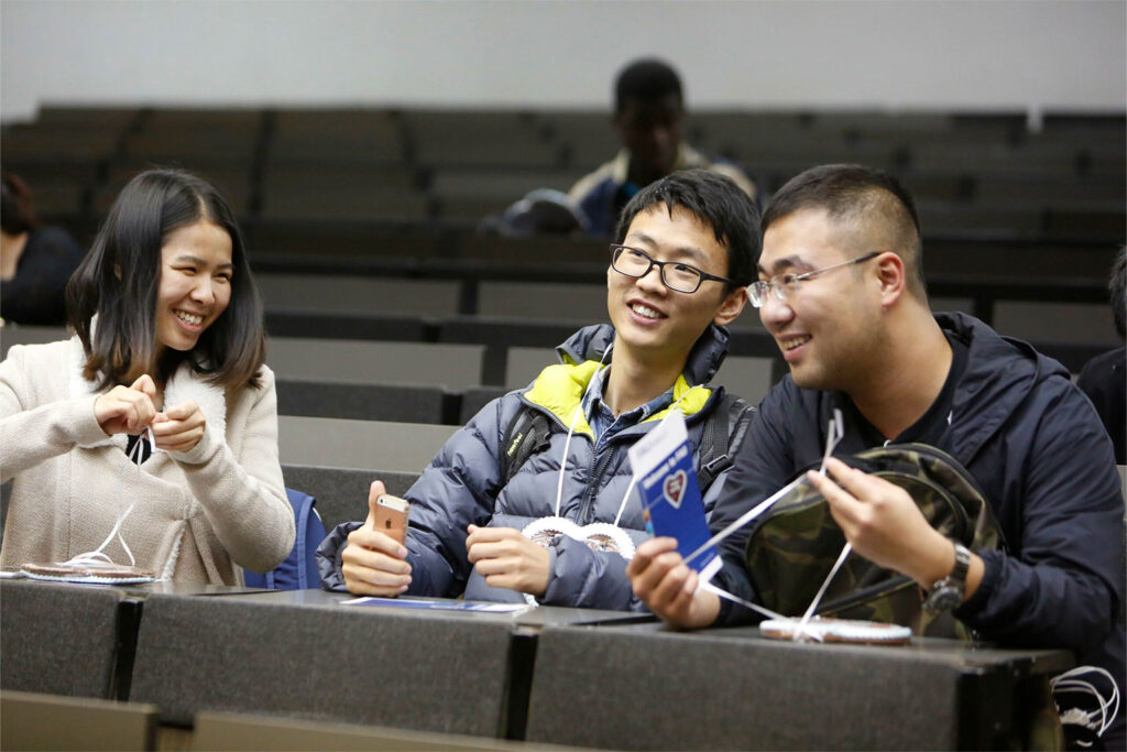 Drei StudentInnen sitzen im Hörsaal und unterhalten sich.